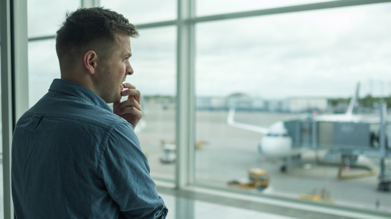 Hombre mirando nerviosamente por la ventana en el aeropuerto