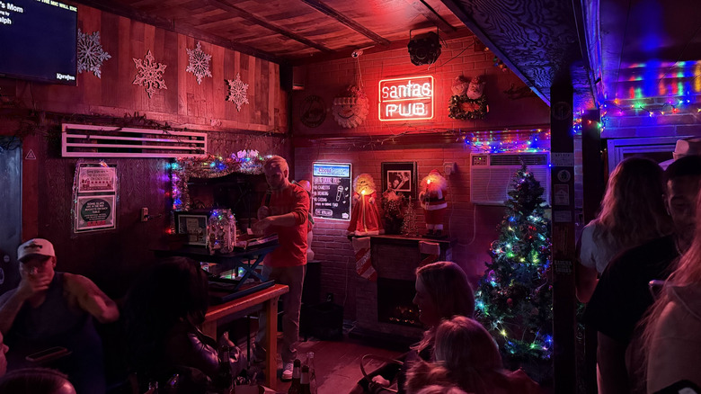 El interior del Santa's Pub, que muestra luces de neón, decoración navideña y un escenario de karaoke.