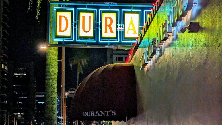 Carteles de Durant's Steakhouse y entrada con palmera por la noche