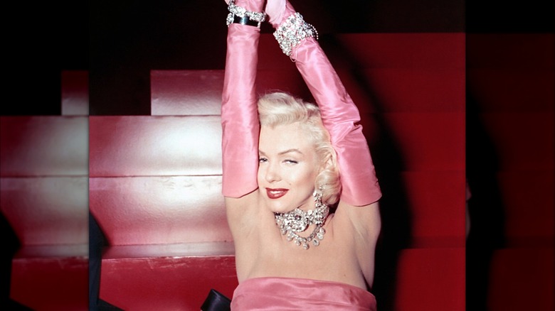 Marilyn Monroe con vestido rosa con guantes hasta el codo, empapada de joyas para 