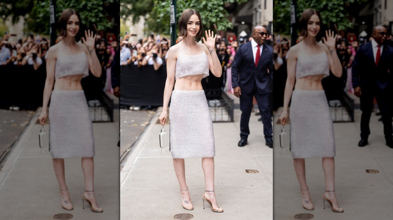Lily Collins saludando con un conjunto blanco transparente en la ciudad de Nueva York
