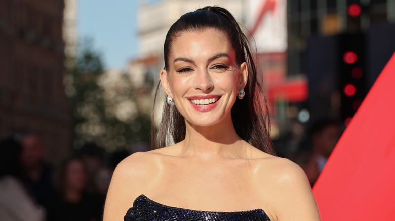 Anne Hathaway sonríe en una foto soleada tomada en un evento de alfombra roja al aire libre