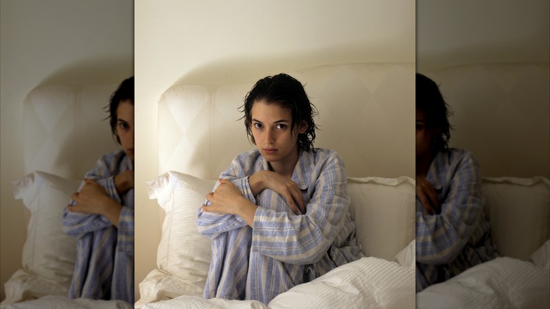 Winona Ryder posa en su cama con un pijama de rayas azules y el pelo mojado.