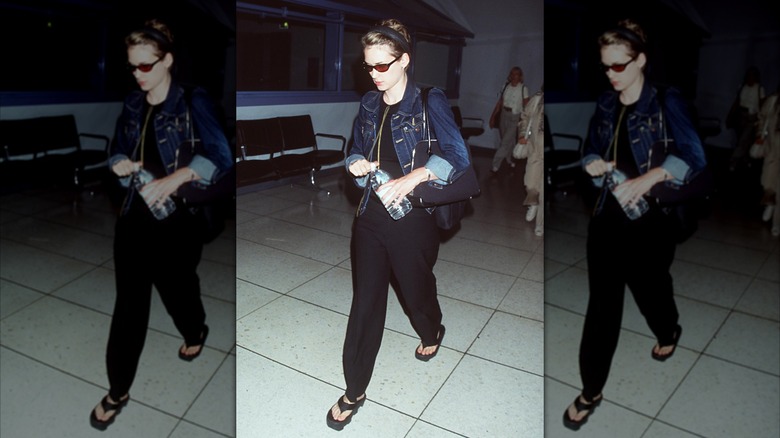 Winona Ryder fotografiada en el aeropuerto con pantalones negros, una chaqueta vaquera y gafas de sol.