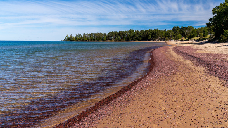 Una vista de Great Sand Bay, que muestra aguas cristalinas, una playa de arena y bosques en la distancia.