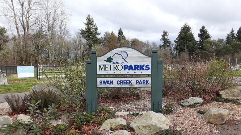 El letrero de Metro Parks Swan Creek Park da la bienvenida a los visitantes frente al parque para perros.