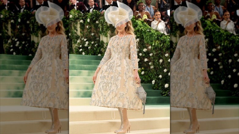 Sarah Jessica Parker posando en la Met Gala de 2024 con un intrincado vestido dorado y un gran sombrero.