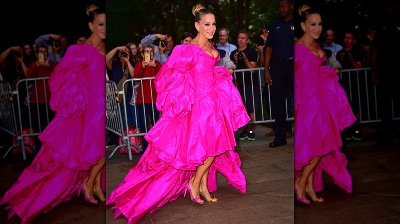 Sarah Jessica Parker posando afuera en un evento en 2019 con un vestido rosa ondulado.