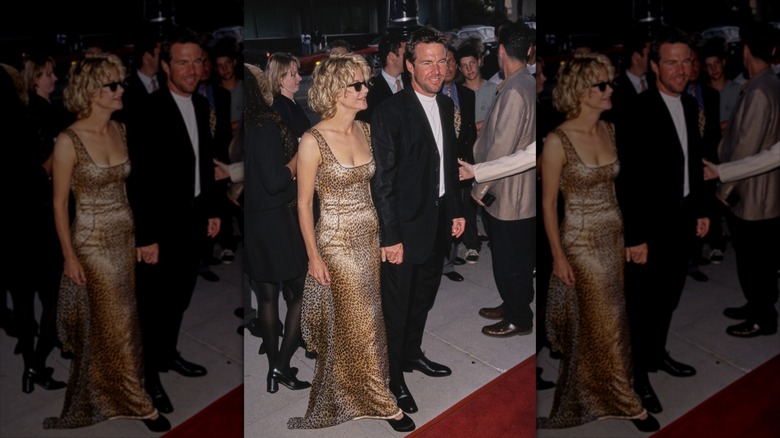 Meg Ryan con un vestido dorado y gafas de sol posando con Dennis Quaid de traje en un evento de alfombra roja.