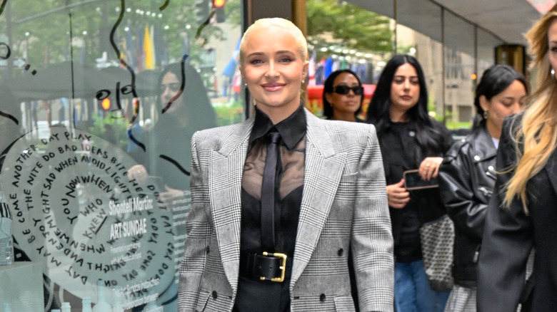 Hayden Panettiere caminando con camisa transparente, corbata y blazer