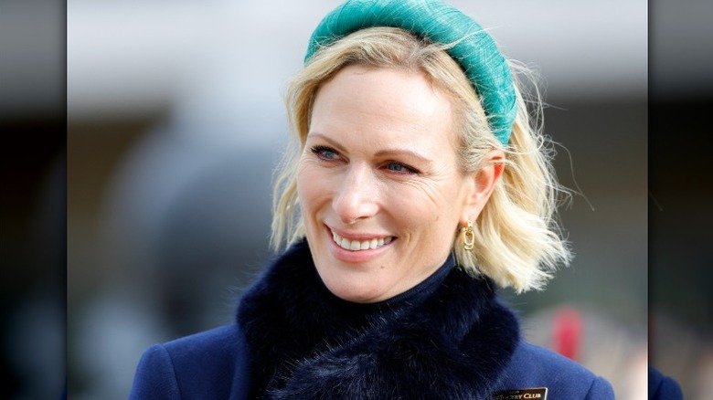 Zara Tindall sonríe en un evento luciendo una gran diadema verde