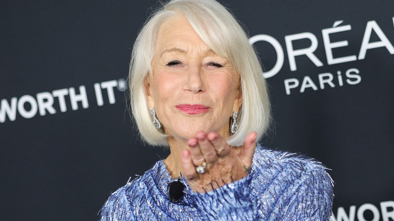 Helen Mirren luciendo un vestido azul y lanzando un beso en la alfombra roja.