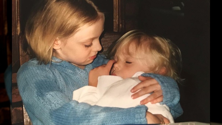 La joven Dakota Fanning sostiene en sus brazos a una pequeña dormida, Elle Fanning.