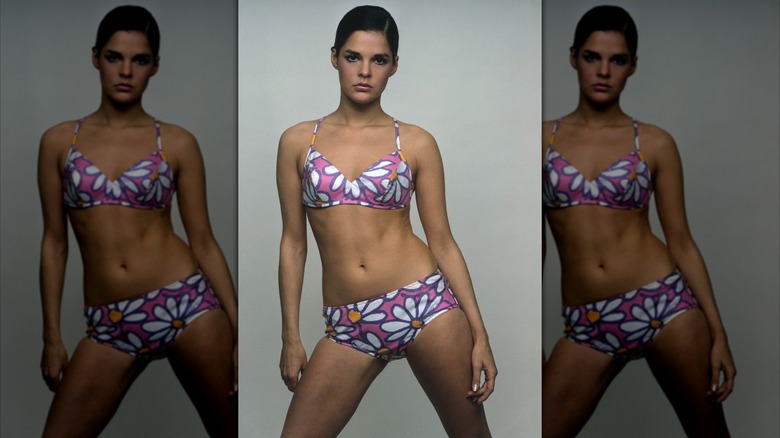 Ali MacGraw posando con un bikini con estampado de margaritas y el pelo peinado hacia abajo.