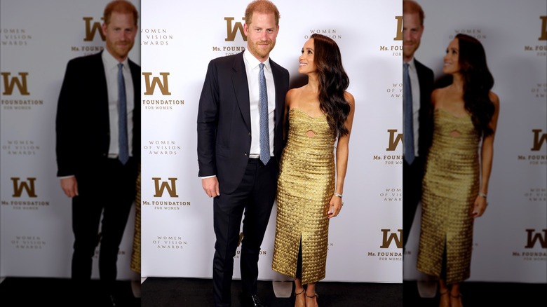 Meghan Markle con un vestido dorado posa junto al príncipe Harry en la alfombra roja de los premios Ms. Foundation Women of Vision Awards.
