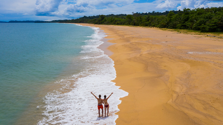 Gente de pie en Bluff Beach en Isla Colón, Panamá, con los brazos en alto