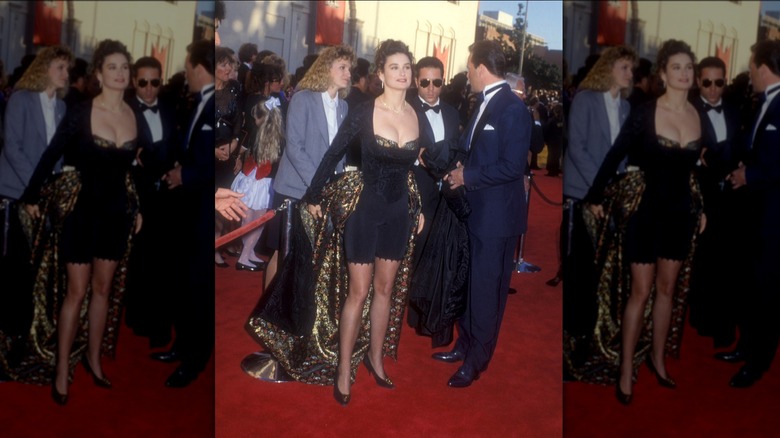 Bruce Willis con esmoquin y Demi Moore con un conjunto azul y negro con capa en la alfombra roja de los Oscar.