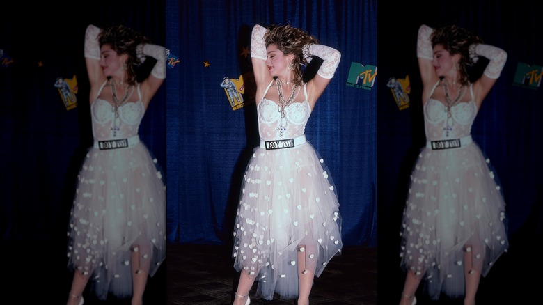 Madonna con las manos en alto vistiendo un traje de encaje blanco, guantes de encaje blanco y un cinturón Boy Toy en los MTV Video Music Awards.