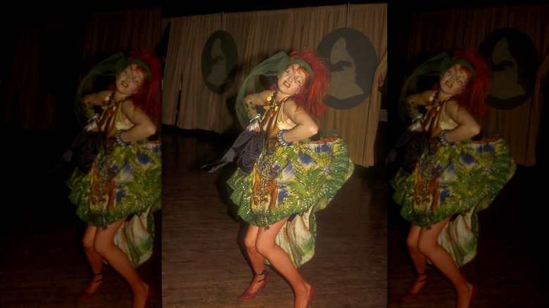 Cyndi Lauper con un vestido verde detallado y una diadema con pañuelo verde y bailando en los Grammy.