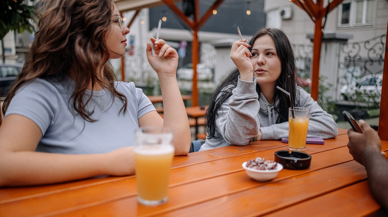 mujeres fumando y bebiendo en una mesa