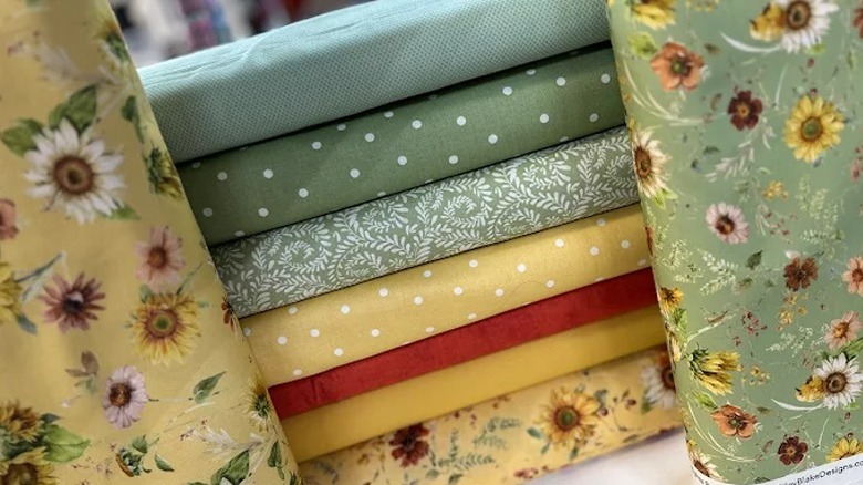 Materiales apilados para colchas en diferentes colores y texturas en Sarah Kathryn's Quilts.