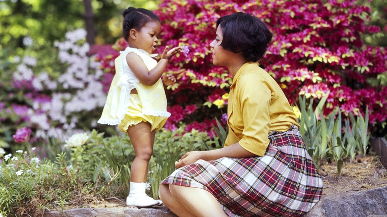 Un bebé mostrando una flor a su madre en los años 1970