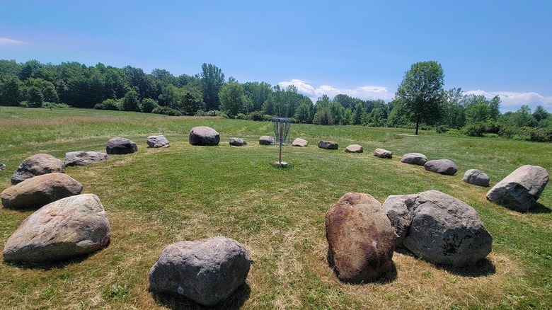 Una canasta de disc golf rodeada de grandes piedras.