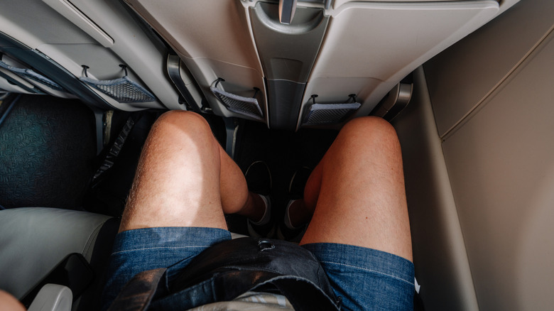 Las piernas de un pasajero de avión con espacio reducido para las piernas.