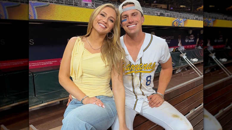 Maggie Sajak viste una blusa amarilla con jeans y posa junto a su novio y jugador de béisbol Jackson Olson en un juego de Savannah Bananas en mayo de 2026.