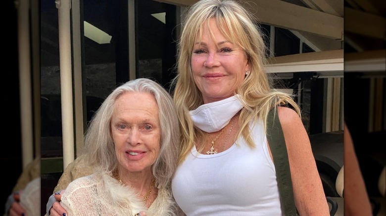 Melanie Griffith sonríe mientras abraza a su madre Tippi Hedren, que luce cabello gris y una suave sonrisa.