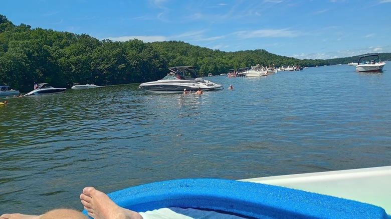 Múltiples barcos a la deriva en las tranquilas aguas del Parque Estatal Lake of the Ozarks, rodeado de exuberantes colinas.