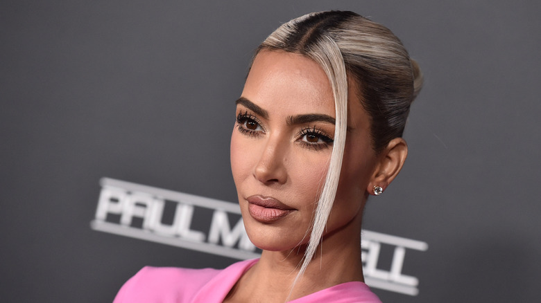 Kim Kardashian posa con su cabello rubio peinado hacia atrás y un top rosa