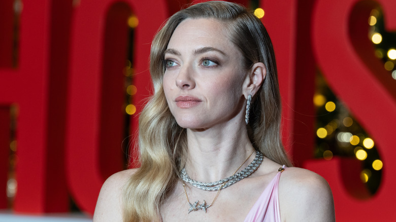 Amanda Seyfried mira hacia la izquierda luciendo dos gargantillas de cristal y aretes de aro.