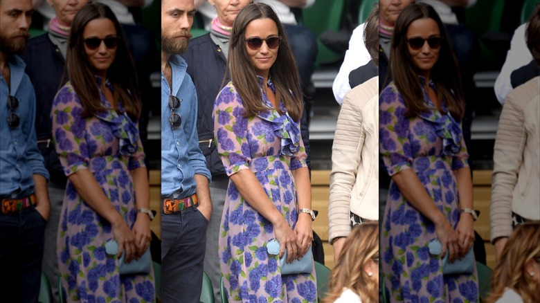 Pippa Middleton con un vestido floral morado con gafas de sol y un bolso de mano azul en Wimbledon en 2016.