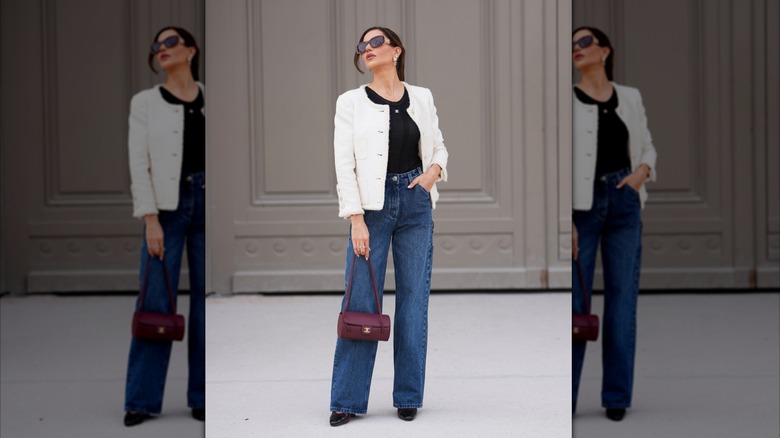 Una mujer vestida con jeans de cintura alta, una chaqueta blanca y una camiseta sin mangas negra.