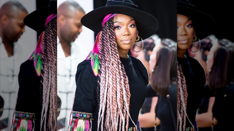 Brandy con trenzas multicolores y un gran sombrero negro.