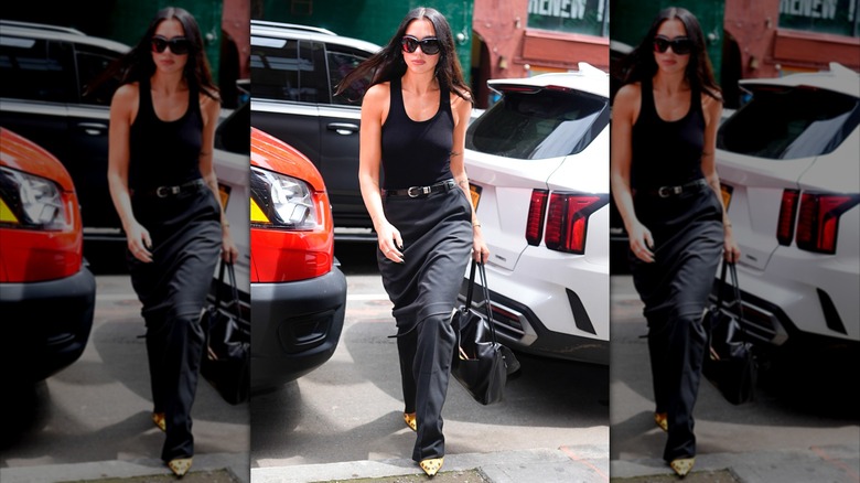 Dua Lipa con una camiseta sin mangas negra con cuello redondo y pantalones negros.