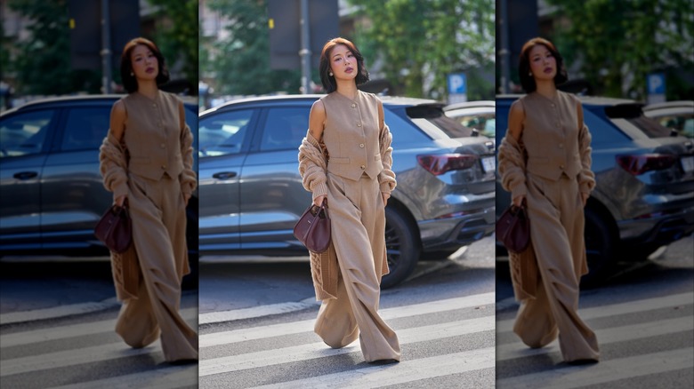 Una mujer vestida con pantalones caqui y un chaleco largo con botones.