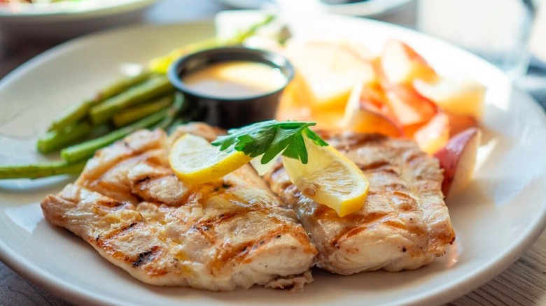 Imagen en primer plano de un plato de pargo rojo de Florida capturado localmente y adornado con una rodaja de limón, uno de los platos principales de mariscos que se sirven en Dry Dock Waterfront Grill.