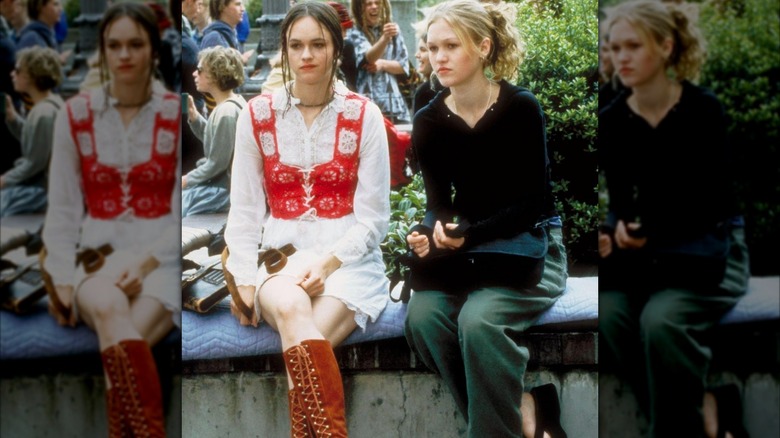 Kat Stratford con pantalones cargo verde oliva y un polo negro de manga larga con chanclas de plataforma.