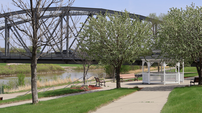 Camino en Red River Greenway en Grand Forks, Dakota del Norte, con un puente al fondo
