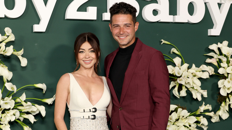 Sarah Hyland con un vestido color crema junto a Wells Adams con un traje color burdeos en la gala Baby2Baby.