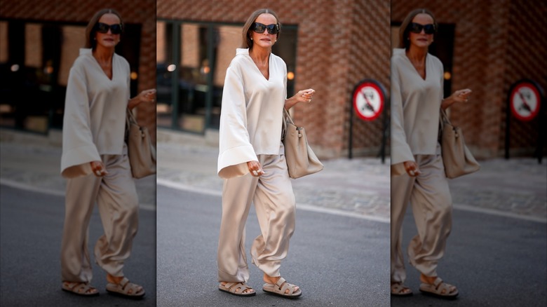 Una mujer que vestía pantalones de raso gris claro.