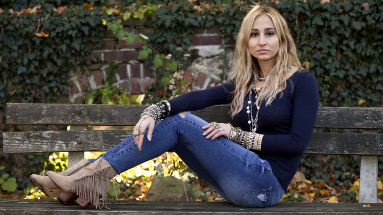 Una mujer vestida con jeans ajustados y botines afuera.