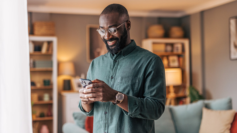 Un hombre sosteniendo un teléfono inteligente mientras sonríe