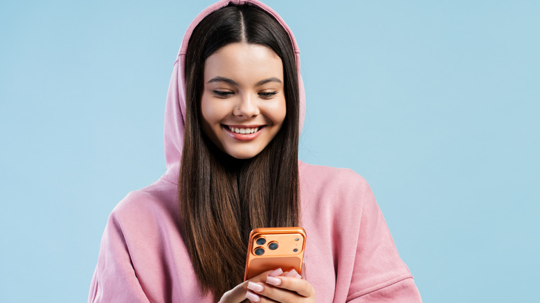 Una niña con una sudadera con capucha y sosteniendo un teléfono inteligente