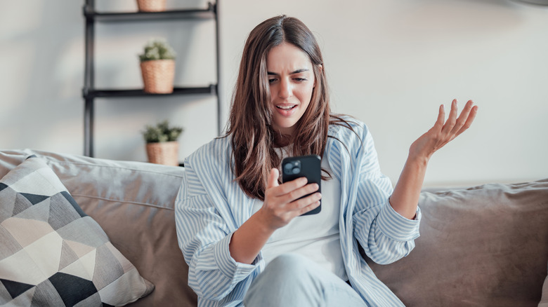 Una mujer mirando su teléfono con exasperación.