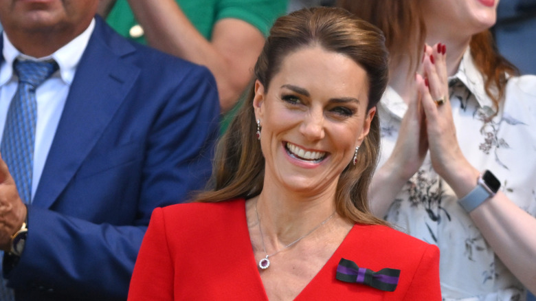 Kate Middleton sonriendo mientras luce un vestido rojo