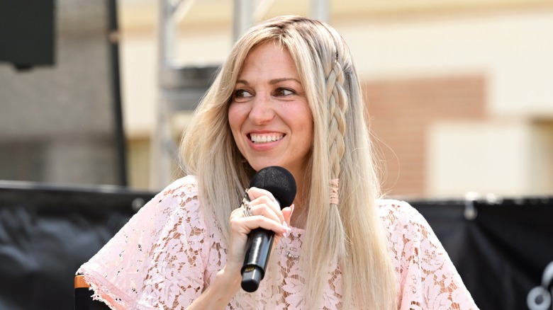Debbie Gibson llevaba su largo cabello rubio suelto con una trenza suelta a un lado y una camisa de encaje rosa pálido mientras hablaba en el Festival de Libros de Los Angeles Times 2026 en Los Ángeles.