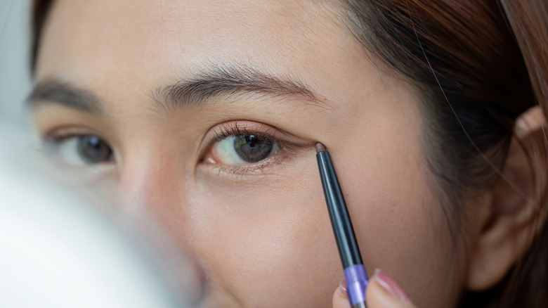 Primer plano de una mujer aplicando un sutil delineador de ojos